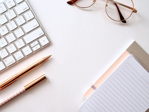 keyboard, glasses pens and paper on desk