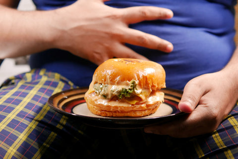 Person holding stomach and holding a burger